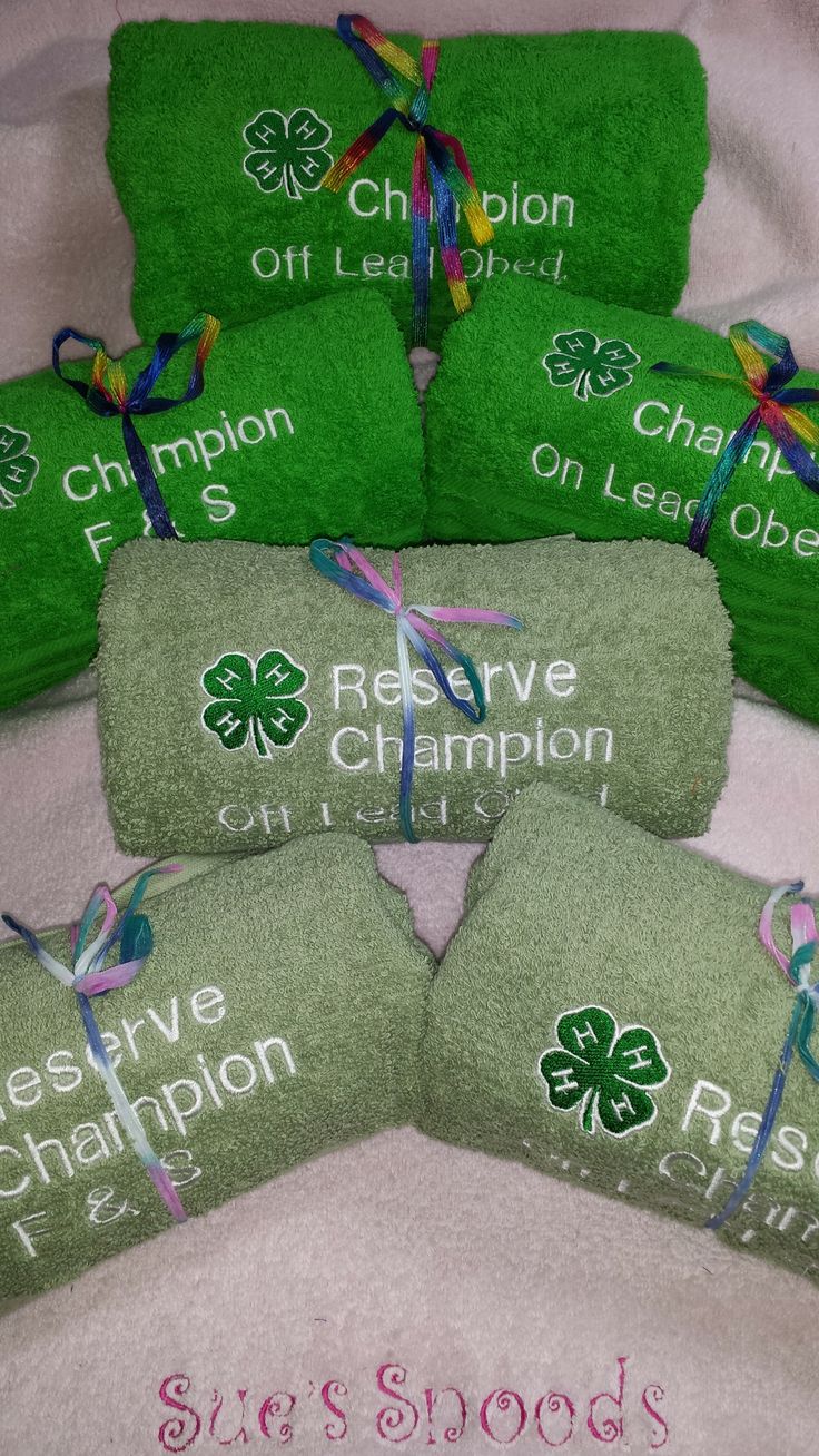 four green towels with shamrocks on them and ribbons tied around them, all in the same color