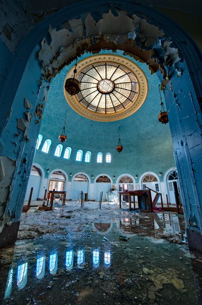 the inside of an abandoned building with peeling paint on the walls and ceiling, looking up into the dome