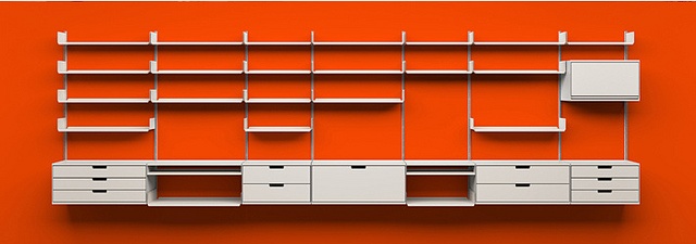 an orange wall with white shelves and drawers