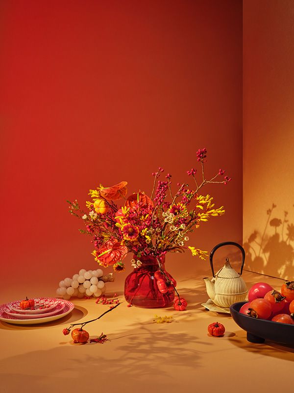 an arrangement of flowers and fruit on a table