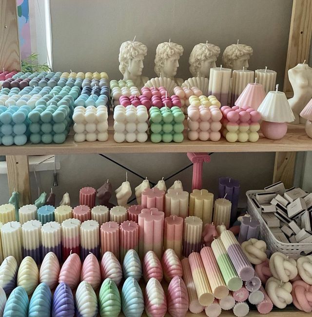 there are many different colored candles on the shelves