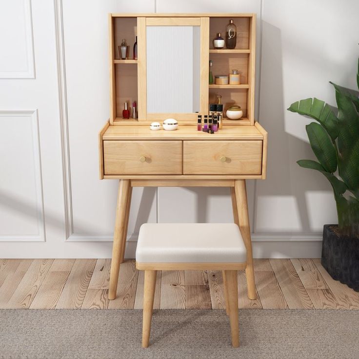 a wooden dressing table with a mirror, stool and potted plant next to it