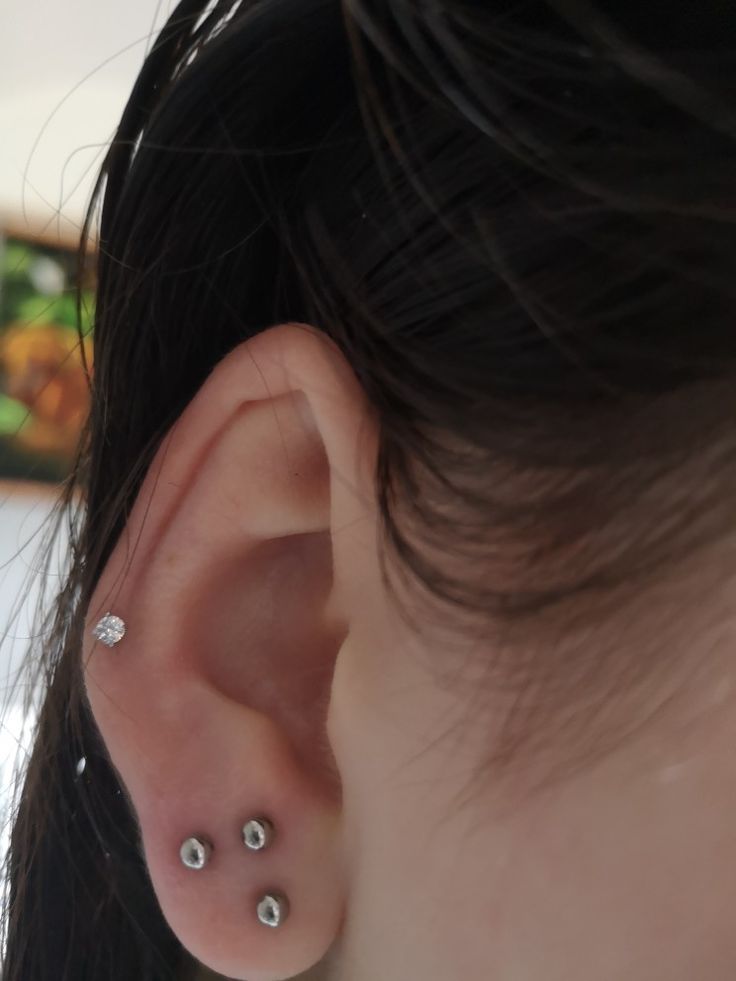 a woman's ear with three piercings on it