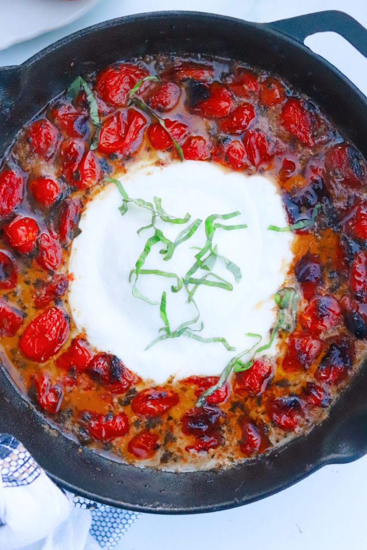 a skillet with tomatoes and sour cream in it