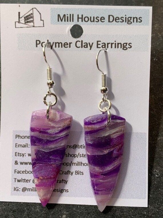 Handcrafted polymer clay earrings. Lightweight and suitable to wear with many different style outfits. The design has been created with translucent clay to make a purple faux crystal  and sealed with resin to protect the surface and add shine Size approximately 3.5x1.5cms. Drop from top of wire 5.5cms Silver plated earring wires  Number 24 purple translucent faux crystal Handmade Purple Crystal Drop Earrings, Trendy Resin Earrings As Gift, Single Dangle Resin Earring, Handmade Trendy Lavender Jewelry, Trendy Handmade Lavender Jewelry, Trendy Nickel-free Purple Earrings, Unique Purple Earrings With Ear Wire, Unique Single Purple Earring, Trendy Lavender Earrings For Gift