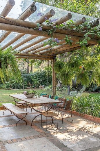 an outdoor dining area with table, chairs and pergolated roof in the background