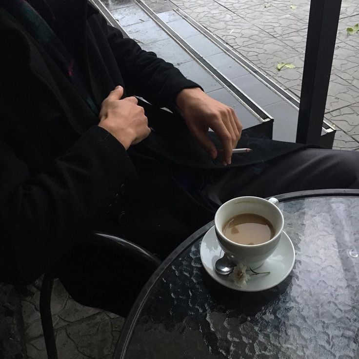 a man sitting at a table with a cup of coffee in front of him on his lap