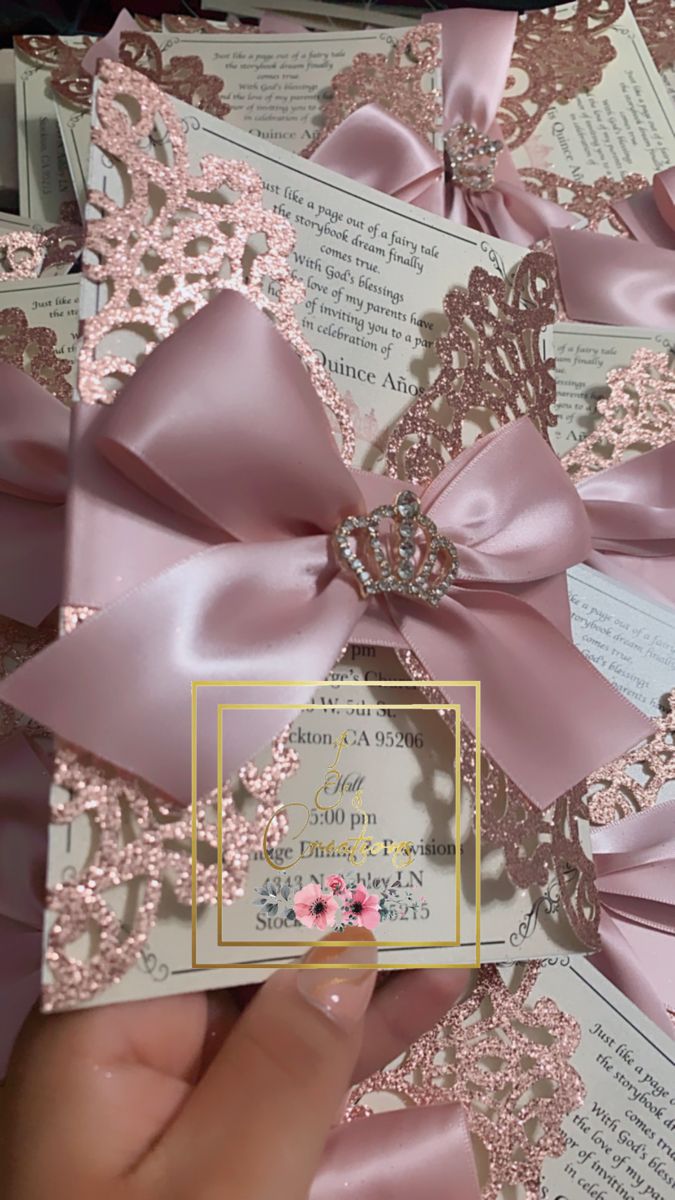 a person is holding up some pink paper with lace and bows on it in front of an open book