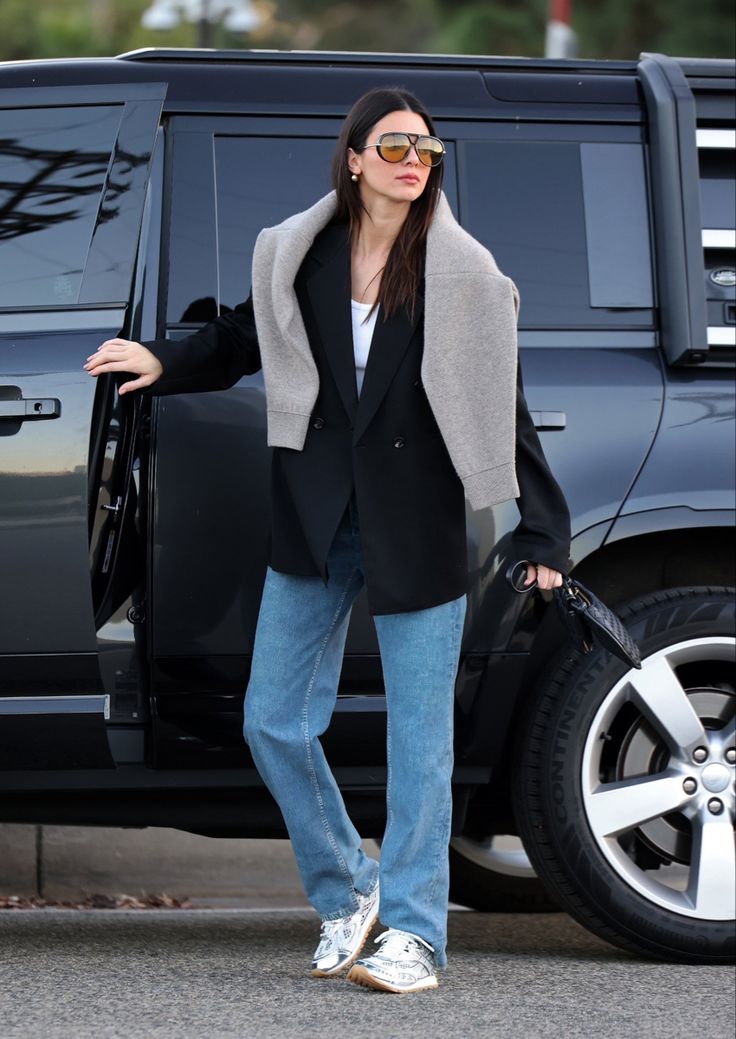 a woman standing in front of a black suv with her hand on the door handle