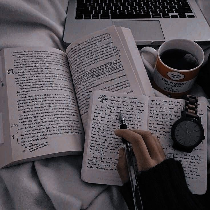 an open book, watch, and pen on a bed with a cup of coffee