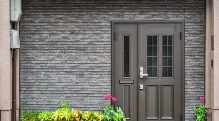 the front door to a building with potted plants and flowers in front of it