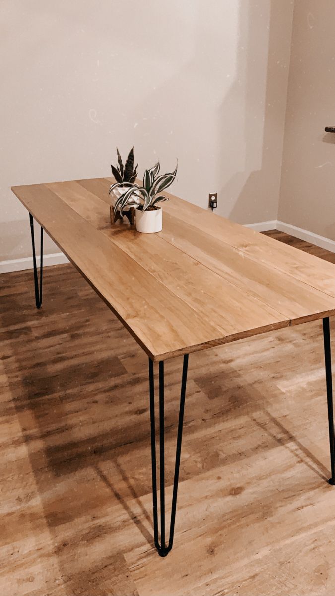 a wooden table with black hairpinks and a potted plant sitting on it