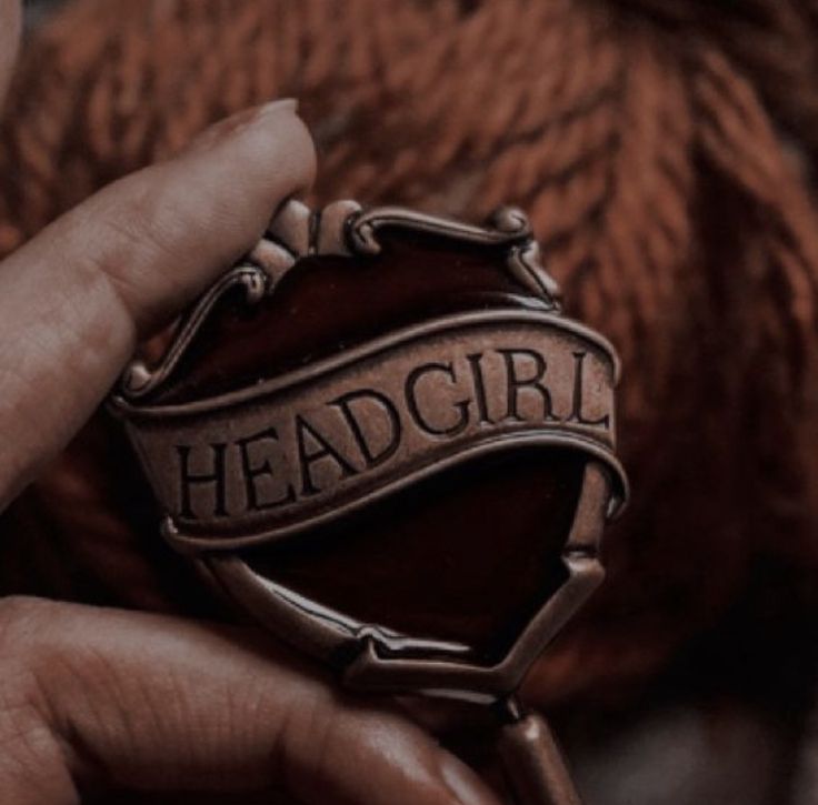 a person holding a badge with the word headgirl on it