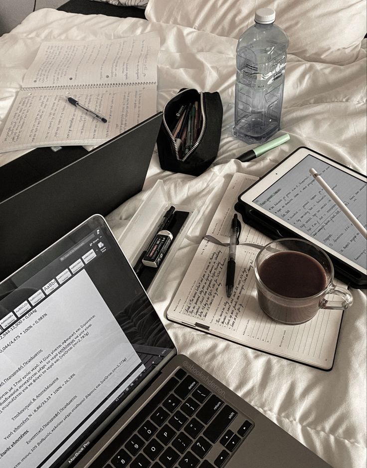 an open laptop computer sitting on top of a bed next to a cup of coffee