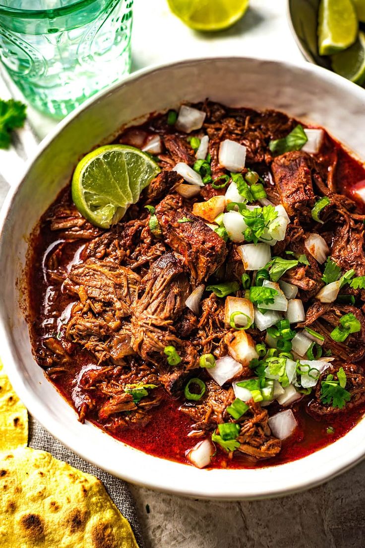 a bowl filled with beef and onions next to tortilla chips