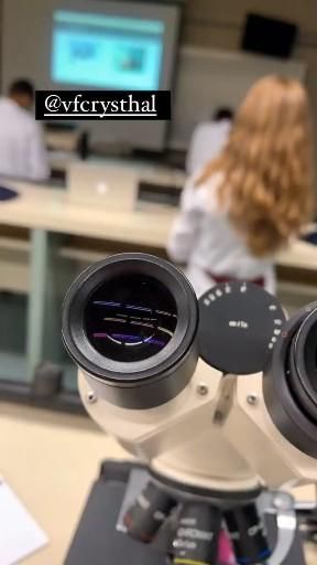 a woman looking through two binoculars at another person in the background