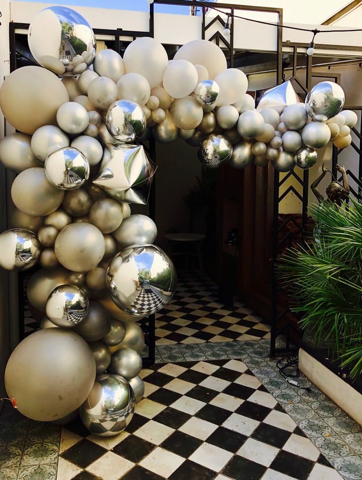 silver and white ornaments hanging from the ceiling in front of a building with black and white checkered flooring