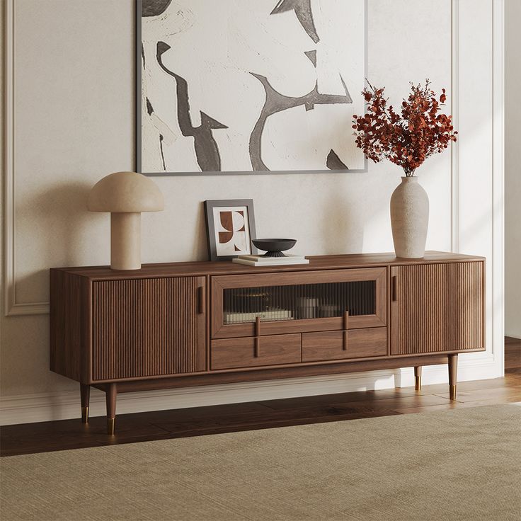 a vase with flowers on top of a wooden entertainment center in a living room next to a painting