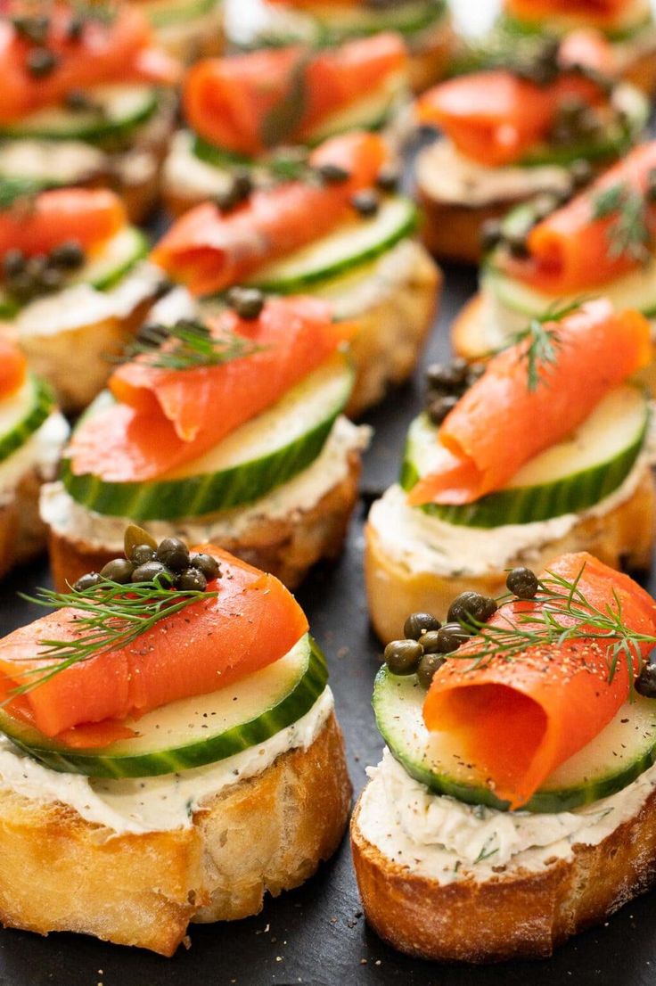 small sandwiches with smoked salmon, cucumbers and capers on them are ready to be served