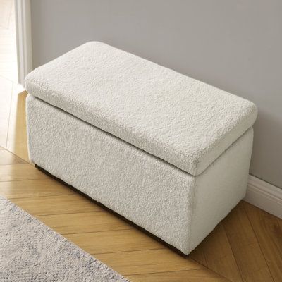 a white storage bench sitting on top of a hard wood floor next to a wall