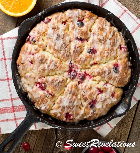 a skillet filled with fruit on top of a table next to an orange slice