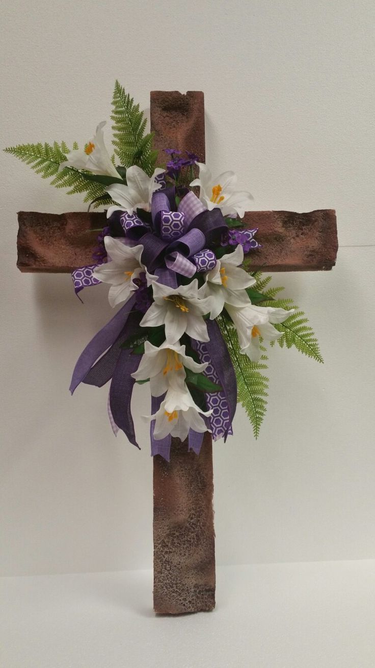 a cross decorated with flowers and greenery