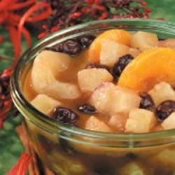 a glass bowl filled with fruit and raisins on top of a wooden table