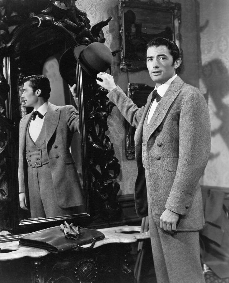 an old photo of two men standing in front of a mirror and pointing at something