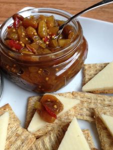 some crackers are on a white plate with cheese and olives in a jar