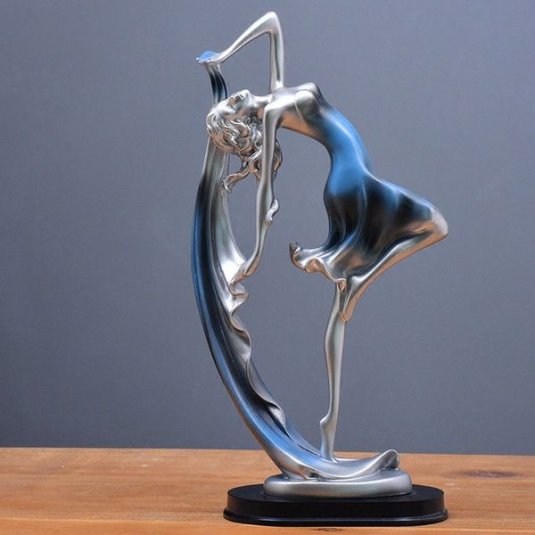 a silver and blue figurine sitting on top of a wooden table next to a gray wall