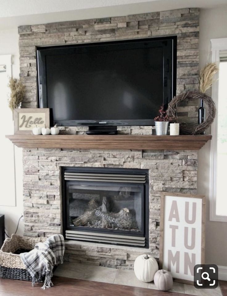 a living room with a fireplace, television and other decorations on the mantels