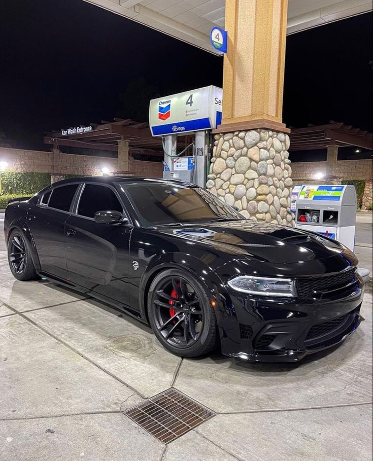 a black car parked in front of a gas station