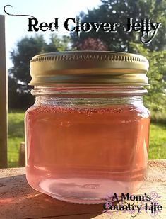 a jar filled with pink liquid sitting on top of a wooden table next to trees