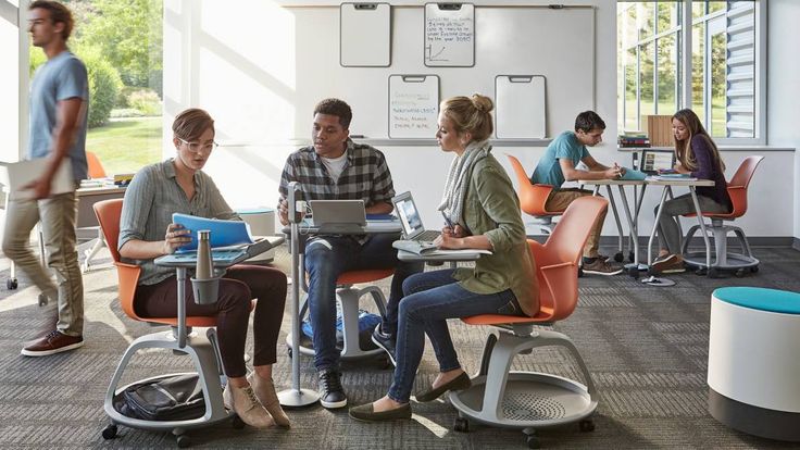 people sitting at desks in an office with computers and laptops on their laps