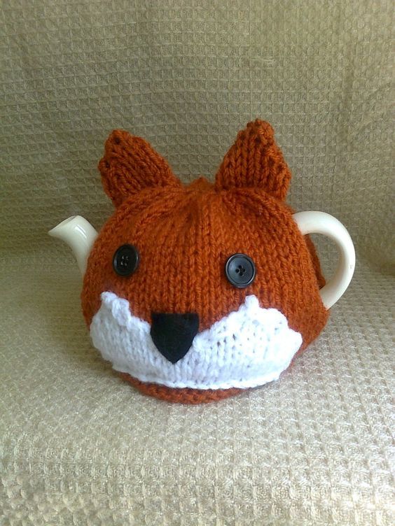 a knitted animal head sitting on top of a couch next to a coffee cup