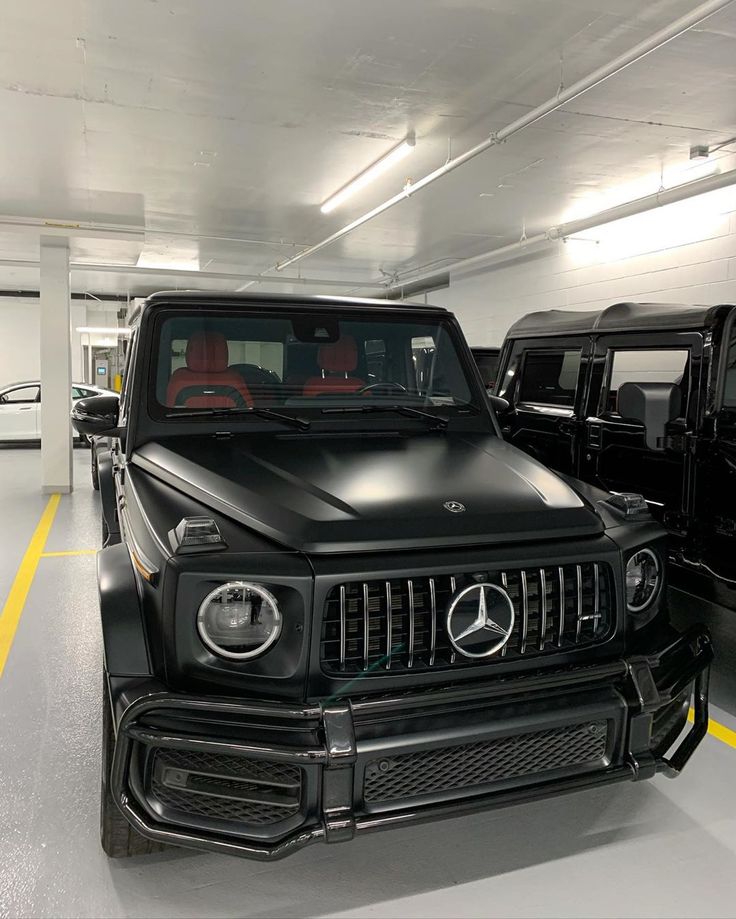 two mercedes benzs are parked in a parking garage next to each other and one is black