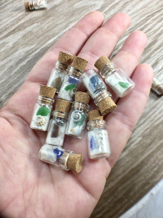 small glass bottles with corks are held in someone's hand