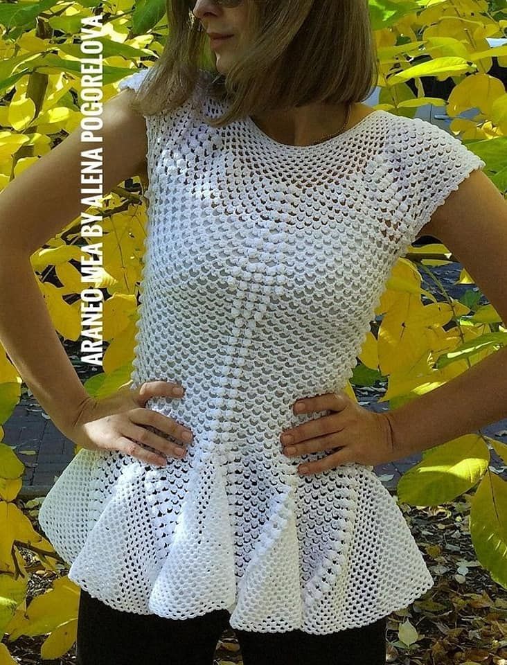 a woman standing in front of yellow leaves wearing a white top with ruffles