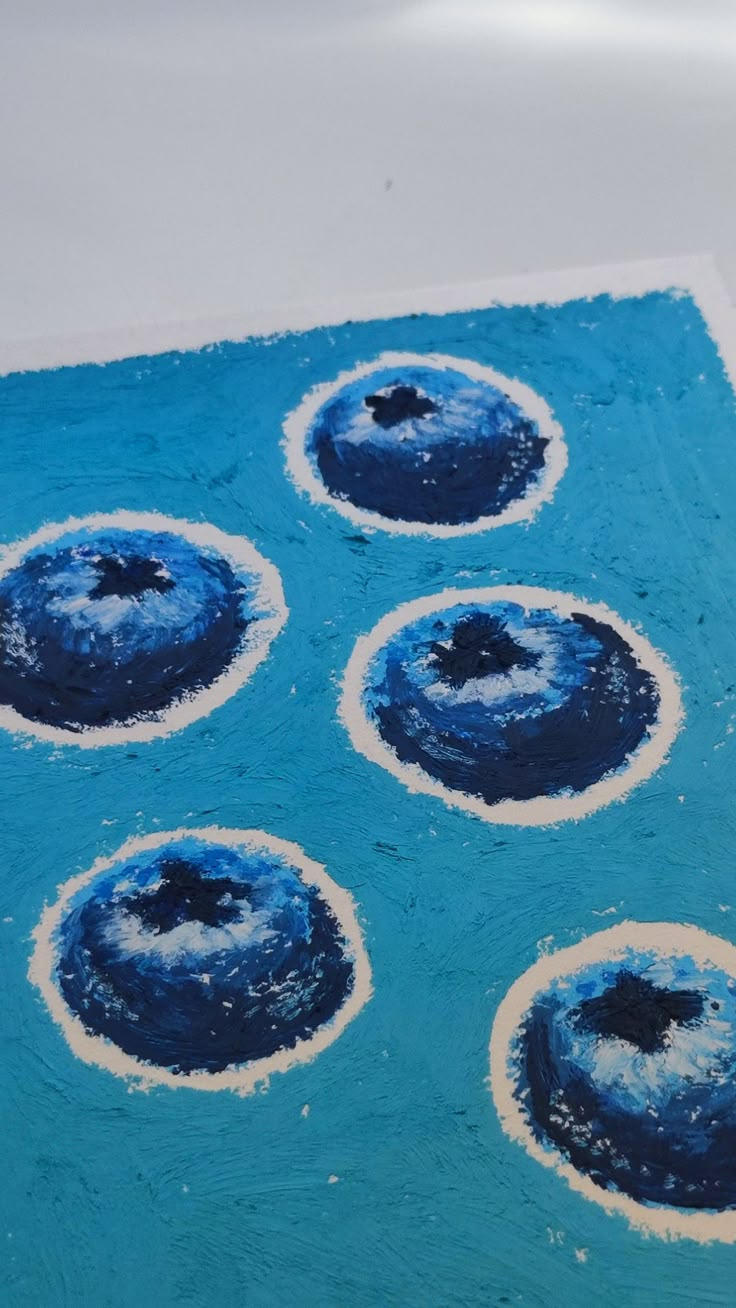 a blue cake with white frosting and four circles in the middle on a table