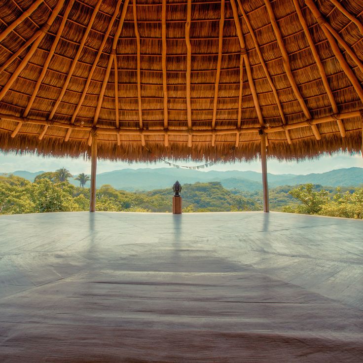 an advertisement for the yoga studio in front of a thatched roof with mountains in the background