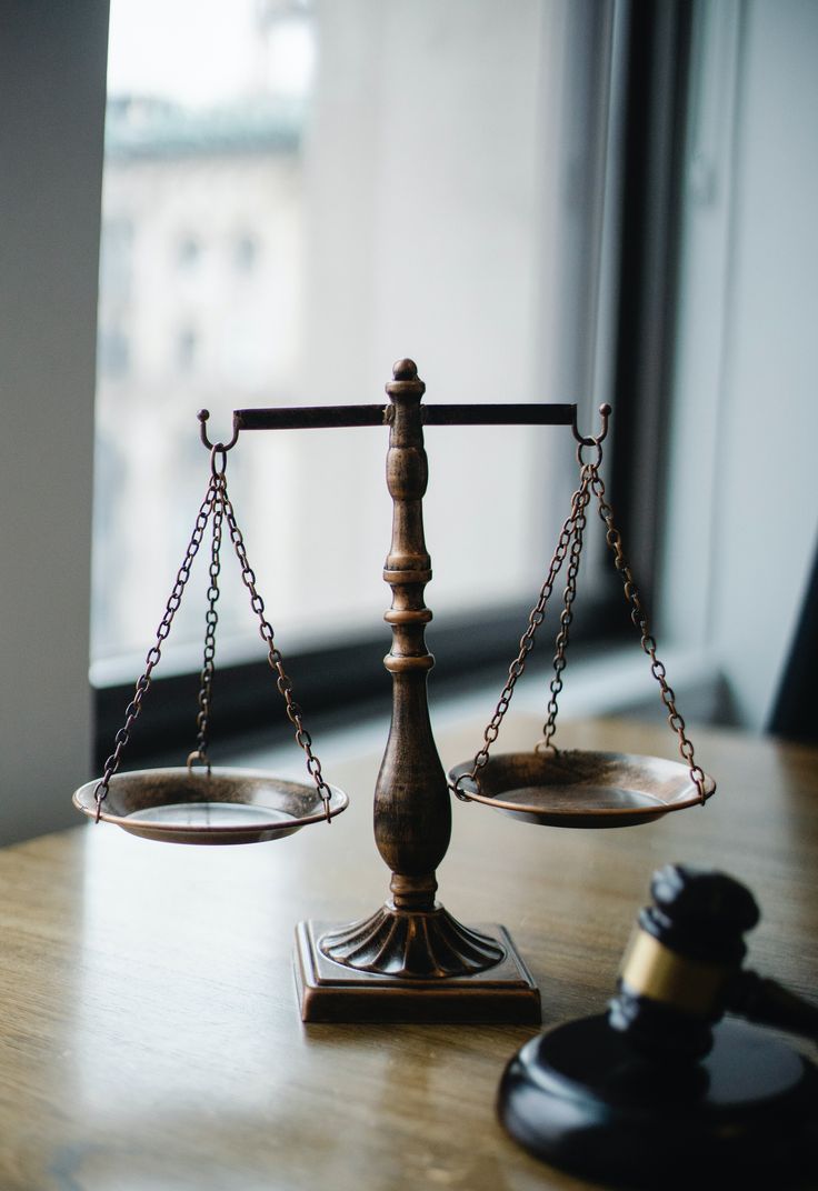 a wooden balance scale sitting on top of a table next to a judge's hammer