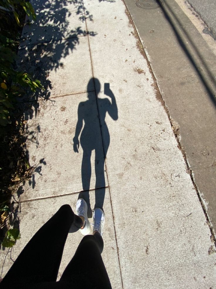 the shadow of a person standing on a sidewalk