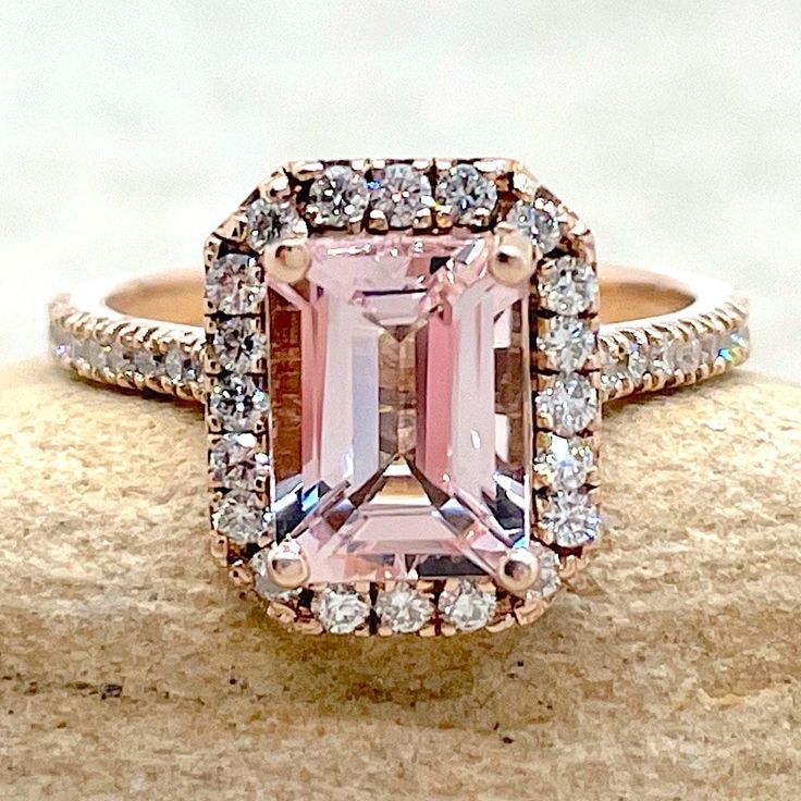 This classic, handmade Light Pink Morganite Ring begins with a stunning, genuine AAA morganite. This is part of our Helena Collection, which features diamonds forming a halo around the center stone, diamonds going half-way down the shank, and diamonds on the prongs under the main stone to give you sparkle from every angle! A cathedral shank raises the center stone so that a matching wedding band can sit flush. Center stone: AAA Rare Light Pink Morganite, Emerald Cut, average 8x6mm and 1.25 carat Pink Morganite Halo Ring, Gia Certified Morganite Jewelry For Anniversary, Pink Radiant Cut Ring With Halo Setting, Classic Pink Cluster Ring With Halo Setting, Pink Diamond Ring With Emerald Cut And Halo Setting, Morganite Rings Gia Certified For Anniversary, Pink Emerald-cut Diamond Ring With Halo Setting, Pink Emerald Cut Diamond Ring With Halo Setting, Pink Emerald Cut Rings With Halo Setting