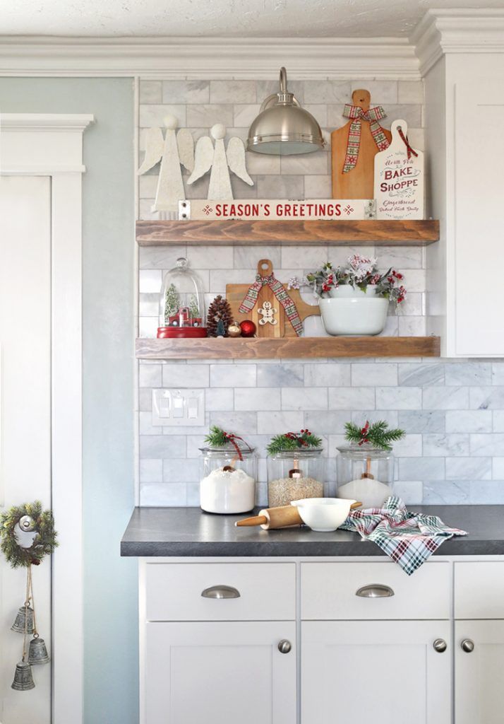 a kitchen with white cabinets and christmas decorations on the shelf above it is decorated for christmas