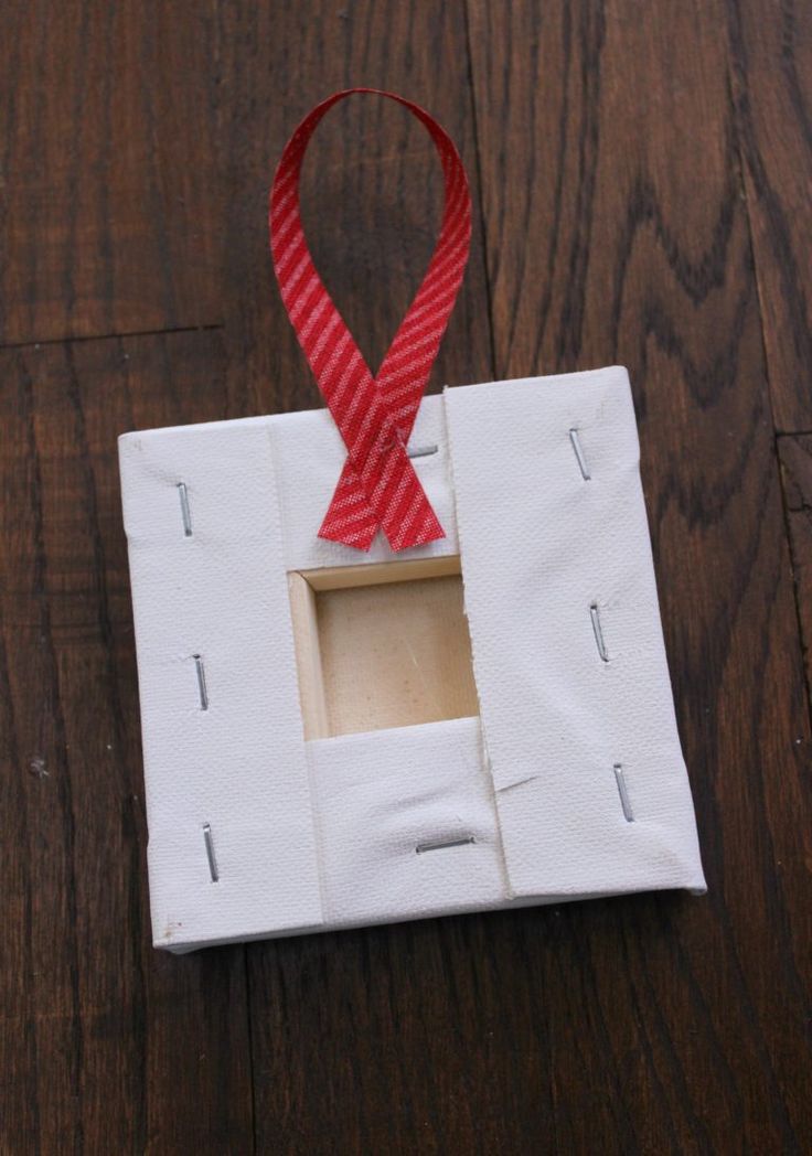 an ornament with a red ribbon hanging from it's side on a wooden table