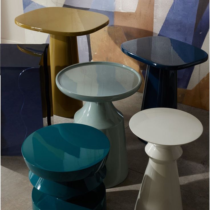 several different colored tables and stools on the floor