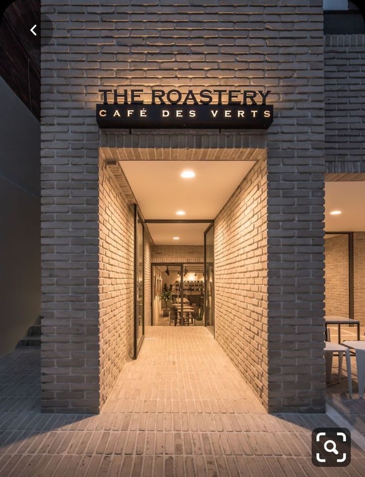 an entrance to a restaurant with brick walls and lights on the outside, along with wooden flooring