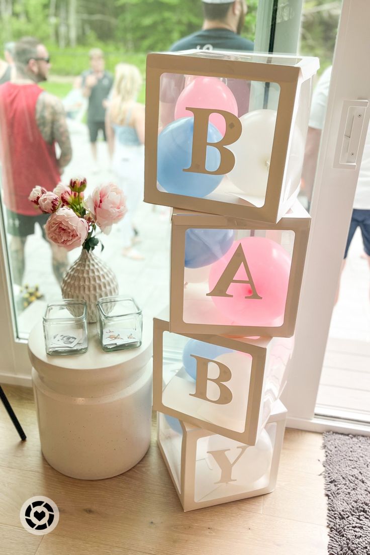 a baby shower sign next to a vase with flowers