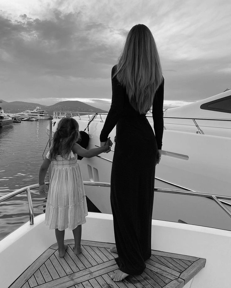 a mother and daughter standing on the deck of a boat