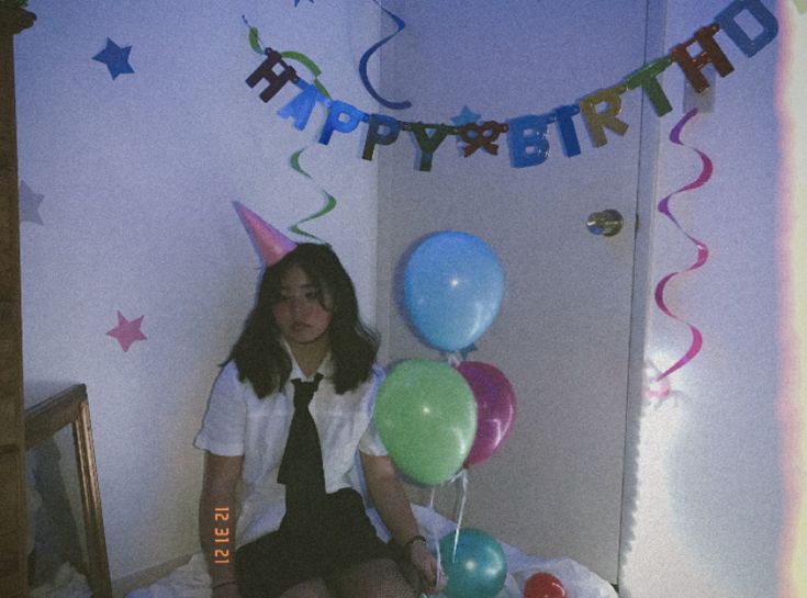 a woman sitting on top of a bed next to balloons